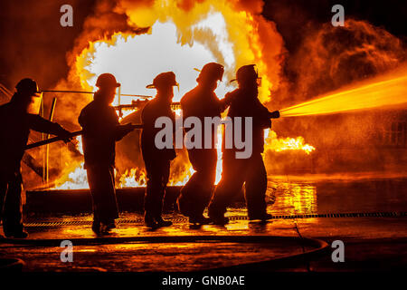 Groupe des pompiers Moving Towards Fire avec flexible Banque D'Images