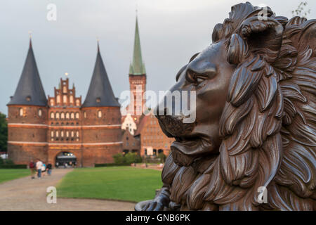 Statue de lion en face de la porte Holstentor et église Saint Pierre, Lübeck, Schleswig-Holstein, Allemagne Banque D'Images