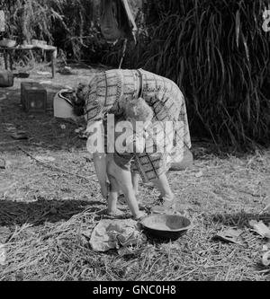 Femme d'emballage Nettoyage travailleur son jeune enfant avec l'eau sale du canal voisin, Belle Glade en Floride, USA, Marion Post Wolcott pour Farm Security Administration, Banque D'Images