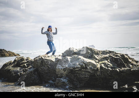 Young Woman Flexing sur les formations rocheuses, parc d'état de Hug Point, Oregon, USA Banque D'Images