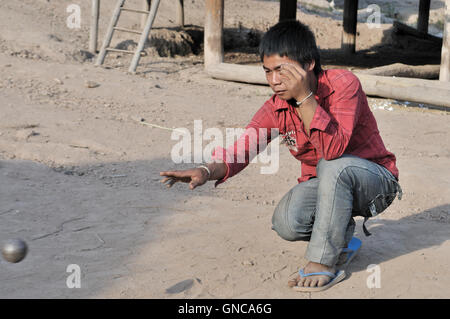 Village le long du fleuve Mékong, le jeune homme jouant Petang Pétanque Banque D'Images