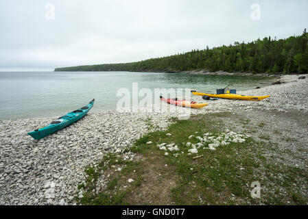 Trois kayaks de mer colorés reste sur un rivage rocailleux Banque D'Images