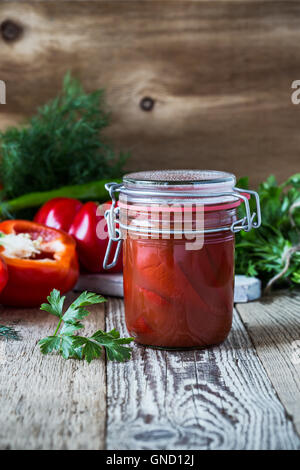 Des poivrons marinés dans du jus de tomate et poivron rouge doux bell sur table rustique Banque D'Images