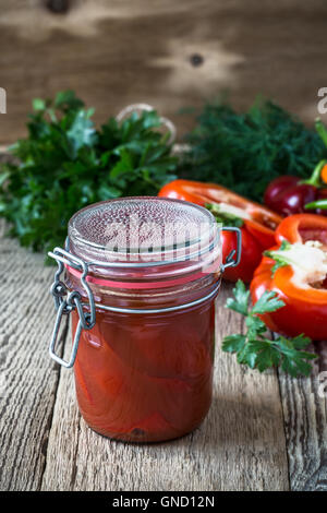 Des poivrons marinés dans du jus de tomate et poivron rouge doux bell sur table rustique Banque D'Images