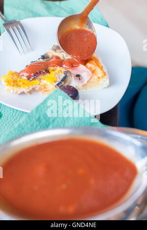 Mettre du ketchup sur pizza slice au restaurant Banque D'Images