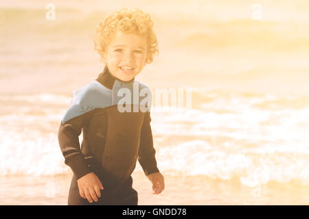 Portrait de jeune garçon par une plage de sable fin de combinaison de plongée