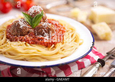 Une assiette avec des spaghetti aux boulettes, garni de fromage parmesan râpé et de basilic. Banque D'Images
