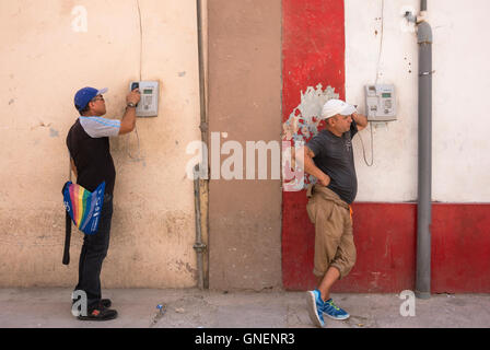 Deux hommes en utilisant les téléphones publics dans une rue de La Havane, Cuba. Banque D'Images