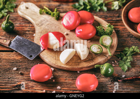 Ciré rouge fromages sur planche à découper en bois Banque D'Images