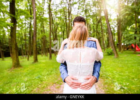 Beau couple de mariés à l'extérieur en vert forêt. Vue arrière. Banque D'Images