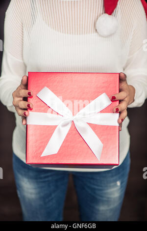 Woman wearing Santa hat tenir red Christmas gift box Banque D'Images