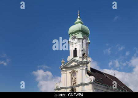 Vue sur la façade de l'église Sainte Elisabeth. Détails baroques, tour avec horloge et toit vert. Ciel bleu avec des nuages blancs. Banque D'Images