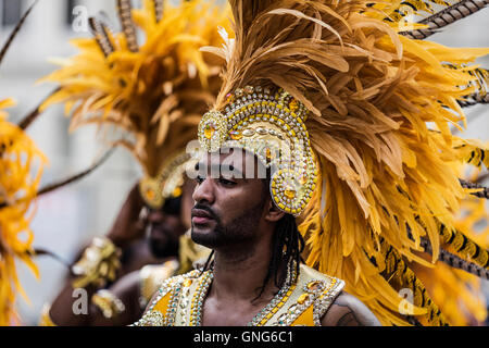 Black man wearing colorful casque jaune avec des plumes jaunes au Notting Hill carnaval de rue dans l'ouest de Londres Banque D'Images