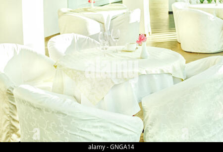 De belles tables et chaises avec une couverture blanche sur la terrasse ensoleillée au matin Banque D'Images