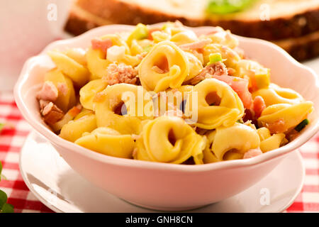 Libre d'un bol en céramique avec une salade de pâtes tortellini avec sur un set de table avec une nappe à carreaux rouges et blancs Banque D'Images