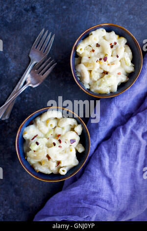 Artichauts crémeux Mac 'N' Cheese dans des bols en céramique avec violet/bleu linin serviettes. Photographié en vue de dessus sur un fond noir et le front Banque D'Images