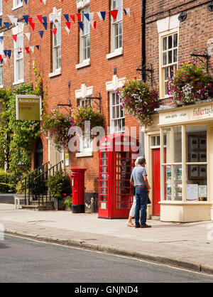 L'homme et la femme à la fenêtre dans les agents immobiliers à Ashbourne Derbyshire en Angleterre avec red post box et téléphone rouge fort Banque D'Images