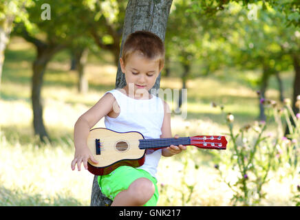 Petit garçon en répétition sur sa guitare acoustique Banque D'Images