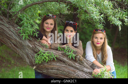 Trois jeunes et belles dames posant dans le parc avec des lunettes colorées Banque D'Images