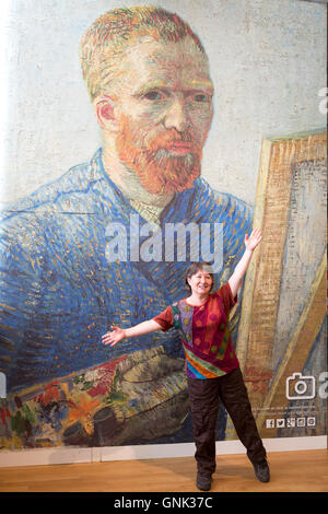 Woman posing in front of poster d'autoportrait de Vincent Van Gogh au Musée Van Gogh à Amsterdam, Hollande galerie Banque D'Images