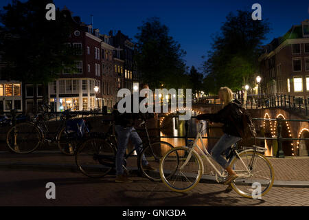 Les cyclistes par ponts illuminés à Kaisersgracht et Leidsegracht, canal ring, quartier du Jordaan, à Amsterdam Banque D'Images