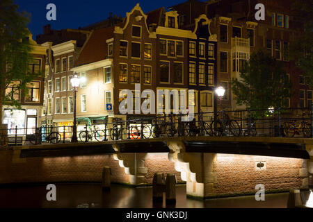 Scène de nuit boutiques et des silhouettes de bicyclettes sur pont, Canal Singel dans 9 rues, Amsterdam, Holland Banque D'Images