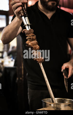 Brochettes de viande à la broche servi à la table dans un restaurant Brésilien. Banque D'Images