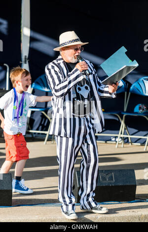 Festival de la semaine folklorique de Broadstairs. Animateur, présentateur, Mick Scott portant un chapeau de paille et le bar rayé noir et blanc costume de parler dans le microphone. Banque D'Images