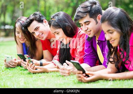 5 jeunes garçons et filles parc amis Chatter Mobile phone Banque D'Images