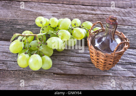 Scellés ancienne bouteille de vin et de raisin blanc sur fond de bois Banque D'Images