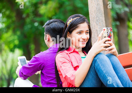 2 Jeune fille et garçon amis College Student Park Bench Sitting Chatting téléphone mobile Banque D'Images