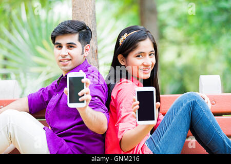 2 Jeune fille et garçon amis College Student Park Bench Sitting montrant la qualité de téléphone mobile Banque D'Images