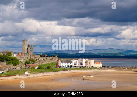 Vue sur l'est ensoleillée à la plage des Sables bitumineux dans les ruines de la cathédrale ville écossaise sous sombre dramatique ciel nuageux. St Andrews Fife Ecosse Royaume-Uni Grande-Bretagne Banque D'Images