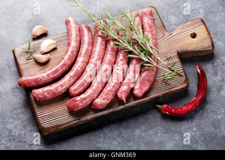 Les saucisses crues et les ingrédients pour la cuisson sur table en pierre Banque D'Images