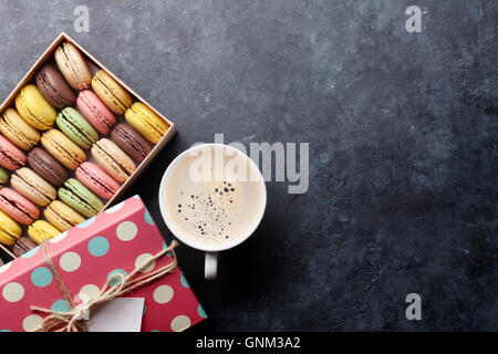 Macarons colorés et café sur table en pierre. Macarons sucrés en boîte cadeau. Top View with copy space Banque D'Images