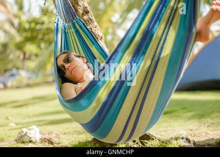 Femme de prendre une sieste sur un hamac dans la plage Banque D'Images