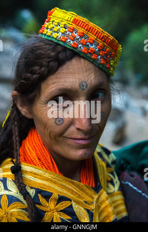 Belle femme Kalasha, avec des tatouages sur le visage, sourit tout en traversant les montagnes de Kalash Valley dans le Chitral, Pakistan Banque D'Images