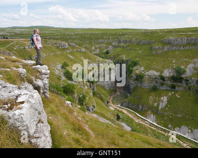 Un female hiker admire la vue sous Gordale Scar, une gorge de calcaire près de Malham dans le Yorkshire Dales National Park Banque D'Images