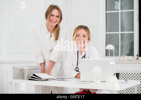 Deux femmes friendly cheerful médecins ou infirmiers isolés dans office smiling and looking at camera Banque D'Images