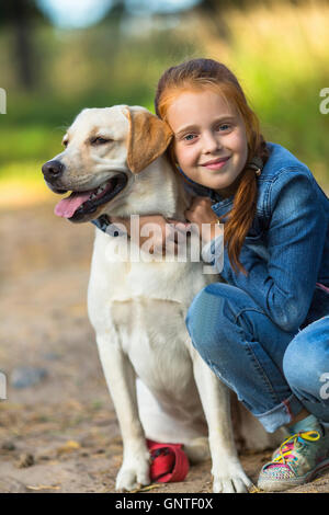 Peu cute girl hugs chien (Labrador) Banque D'Images