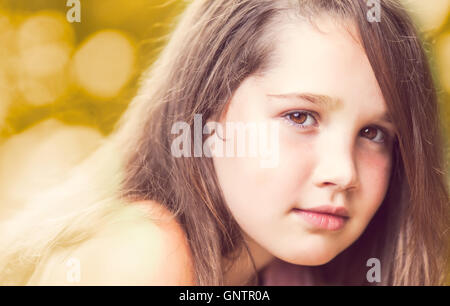 Confident young girl looking at camera smiling sur une journée ensoleillée avec de beaux bokeh background Banque D'Images