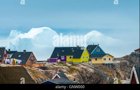 Maisons à Ilulissat avec d'énormes icebergs échoués à l'embouchure de la Fjord glacé à l'arrière-plan, l'ouest du Groenland Banque D'Images