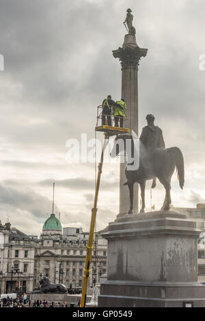 Nettoyage des ouvriers la statue du roi George IV statue sur un ciel nuageux l'après-midi. Lord Horatio Nelson peut être vu au sommet d'une colonne dans l'arrière-plan. Banque D'Images