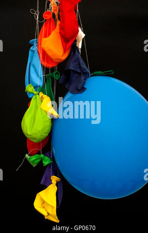 Fin de la partie. Certains ballons dégonflés, rafale et un ballon accroché sur les threads. Fond noir. Banque D'Images