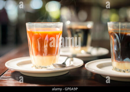 Tradition thaïlandaise du thé chaud avec du lait concentré sucré de style ancien tasse, servi sur table en bois. Banque D'Images