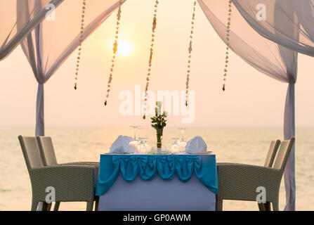 Dîner romantique sur la plage au coucher du soleil. Banque D'Images