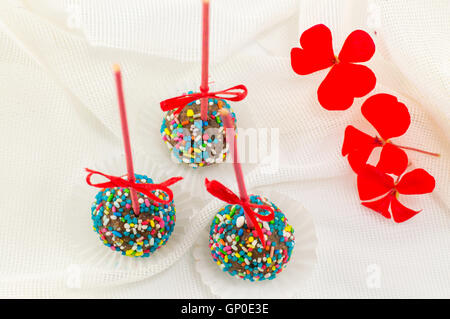 Cake pops sur une table recouverte d'un tissu en soie blanche Banque D'Images