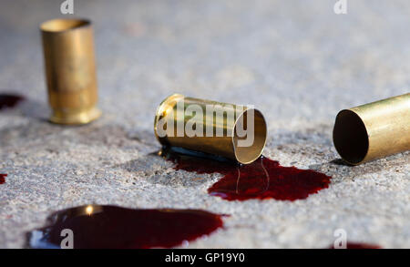 Douilles qui ont été tourné à partir d'un pistolet avec du sang sur le béton Banque D'Images