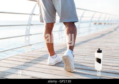 Image recadrée de sportifs jambes faisant des exercices en plein air sur la jetée en bois Banque D'Images