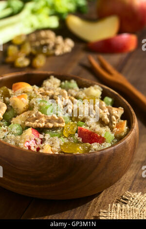 Le quinoa salade Waldorf avec Apple, le céleri, les raisins secs et de noix jaune servi dans un bol en bois, les ingrédients à l'arrière Banque D'Images